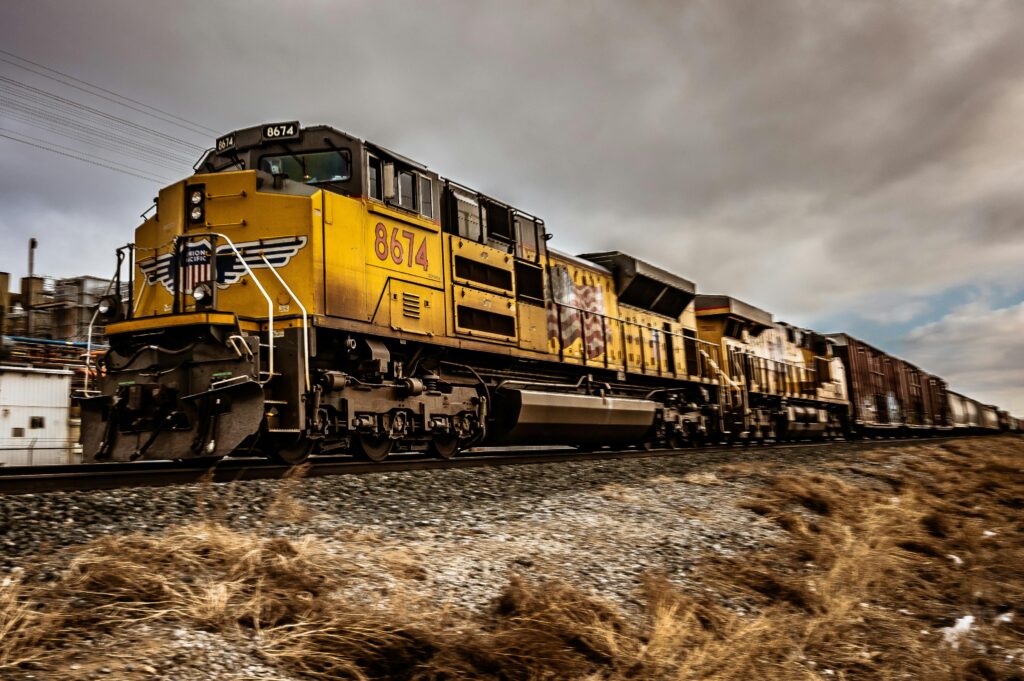 Dynamic shot of a yellow train moving on railway tracks under cloudy skies.