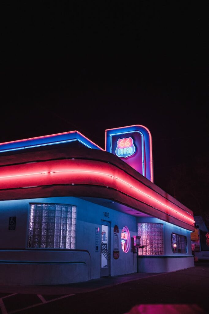 Vibrant neon lights illuminate the iconic 66 Diner in Albuquerque, creating a nostalgic urban night scene.